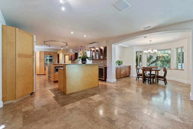 kitchen with a chandelier, wine cooler, a center island, an AC wall unit, and decorative light fixtures