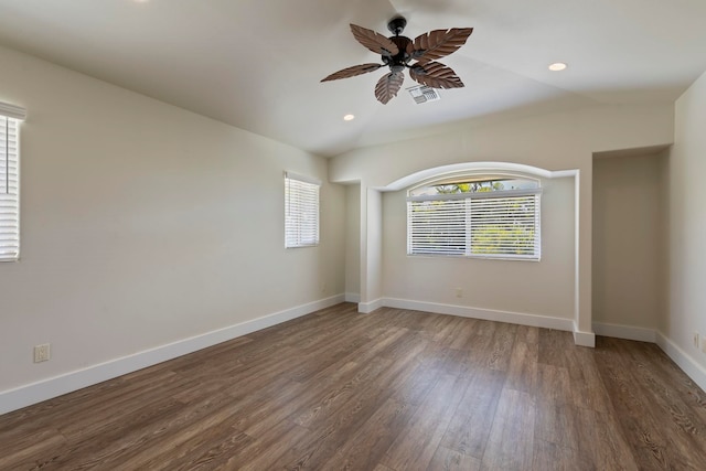 empty room featuring lofted ceiling, dark hardwood / wood-style floors, ceiling fan, and a wealth of natural light