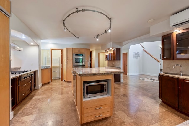 kitchen featuring pendant lighting, sink, a kitchen island with sink, stainless steel appliances, and a wall unit AC