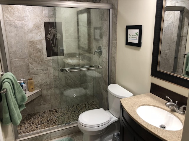 bathroom featuring vanity, a shower with door, and toilet