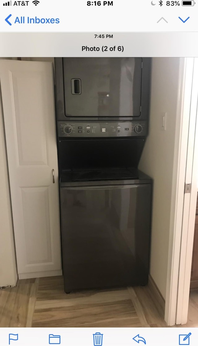 laundry area with light wood-type flooring and stacked washer / dryer