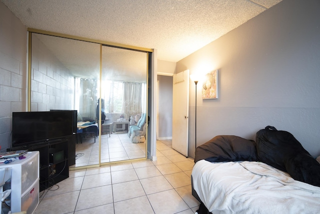 living room featuring concrete block wall, light tile patterned floors, and a textured ceiling