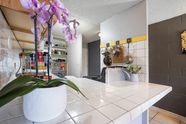 kitchen with tile patterned flooring, tile countertops, and a textured ceiling