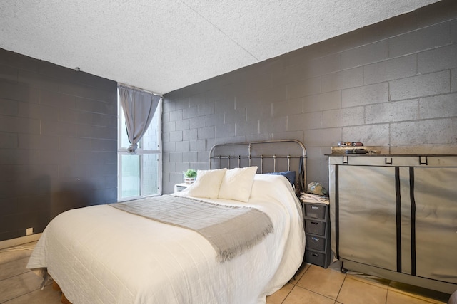 tiled bedroom with concrete block wall and a textured ceiling