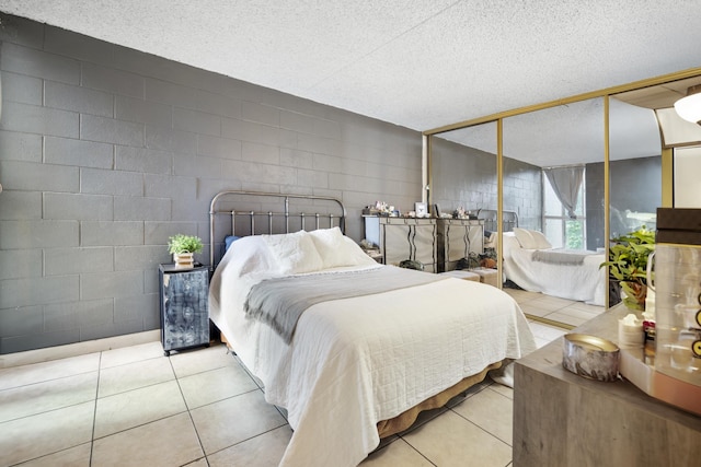 tiled bedroom with a textured ceiling and concrete block wall