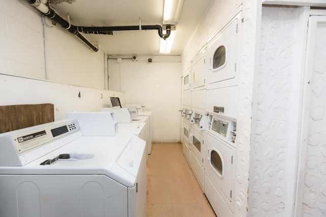 shared laundry area with light tile patterned floors, a garage, stacked washer and dryer, and washing machine and dryer