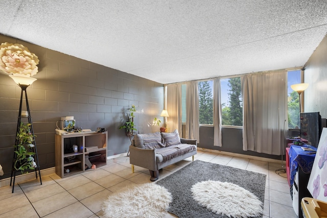 tiled living area with a textured ceiling and concrete block wall