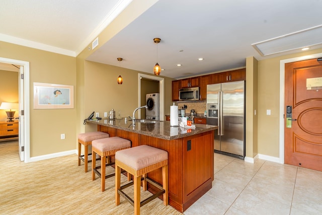 kitchen featuring pendant lighting, backsplash, light tile patterned floors, a kitchen bar, and stainless steel appliances