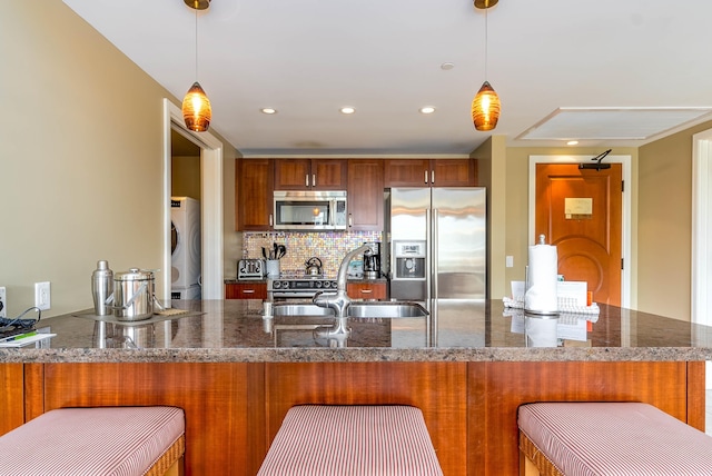 kitchen with backsplash, sink, hanging light fixtures, kitchen peninsula, and stainless steel appliances