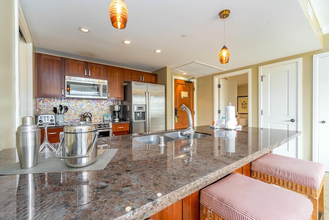 kitchen featuring sink, dark stone countertops, decorative light fixtures, decorative backsplash, and appliances with stainless steel finishes