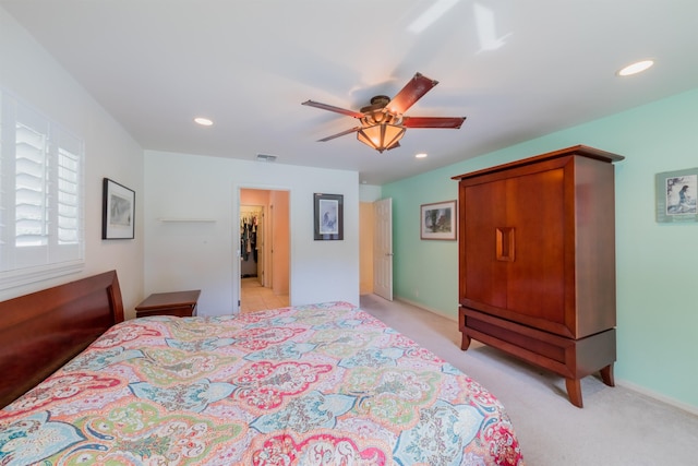 bedroom with light carpet, a walk in closet, and ceiling fan