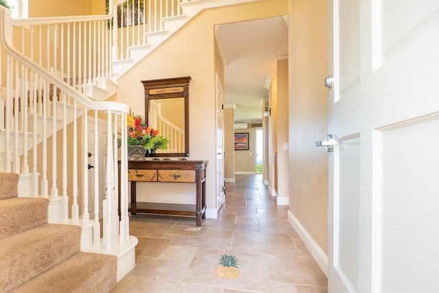 entrance foyer with ornamental molding and a towering ceiling