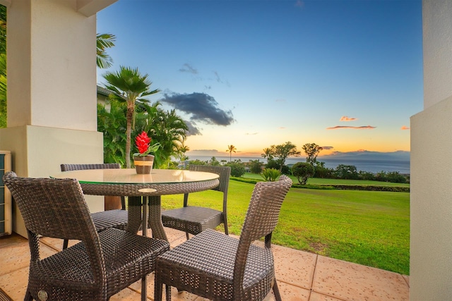 patio terrace at dusk featuring a yard