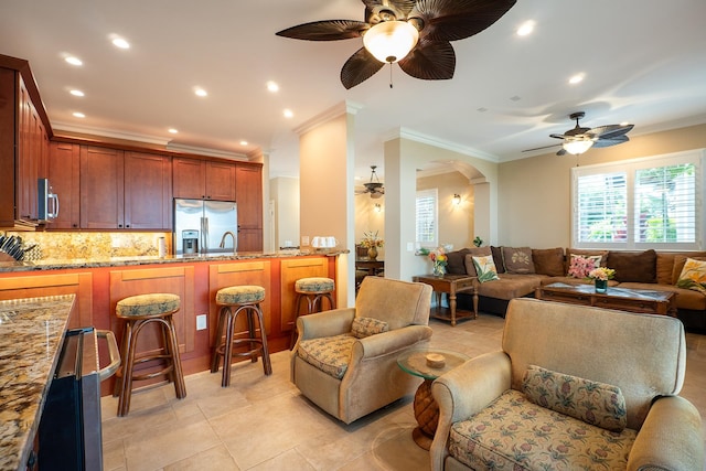 living room with ceiling fan, sink, light tile patterned flooring, and crown molding