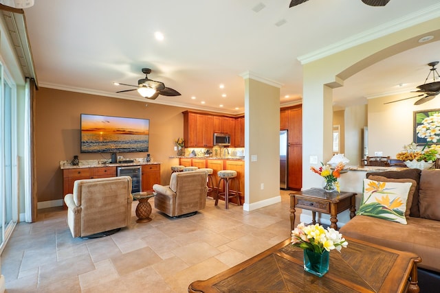 living room with beverage cooler, ceiling fan, and crown molding