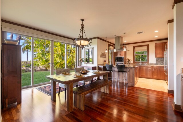 dining area with wood-type flooring, ornamental molding, and sink