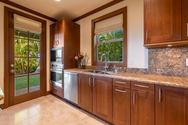 kitchen with tasteful backsplash, light stone counters, ornamental molding, stainless steel appliances, and sink