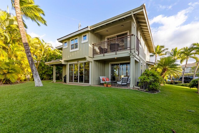 rear view of house with a patio area, a balcony, and a yard