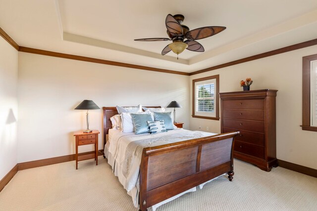 bedroom featuring ceiling fan, light colored carpet, ornamental molding, and a tray ceiling