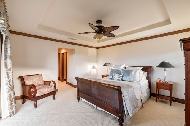 carpeted bedroom featuring a tray ceiling, ceiling fan, and crown molding