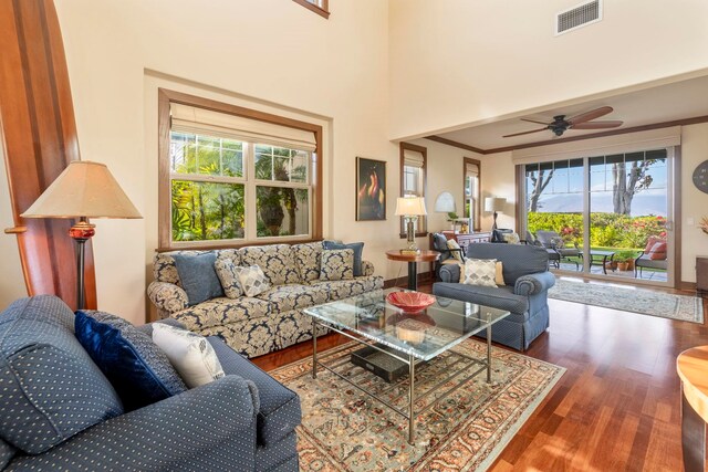 living room featuring ceiling fan, a healthy amount of sunlight, dark hardwood / wood-style flooring, and a towering ceiling