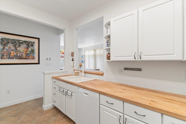 interior space with white dishwasher, wood counters, white cabinets, and a sink