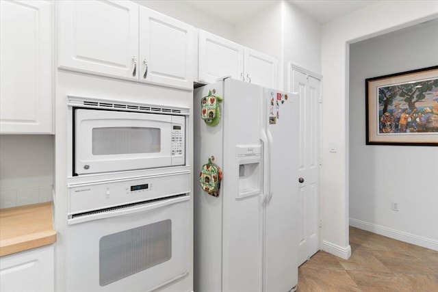 kitchen with white appliances, white cabinets, and baseboards