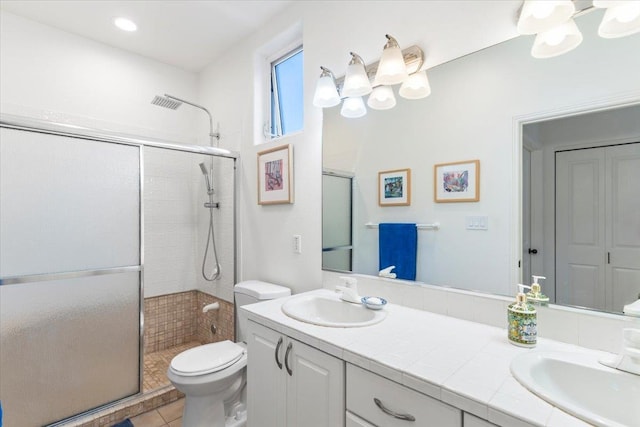 bathroom featuring double vanity, a stall shower, a sink, and toilet