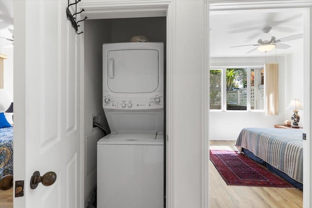 washroom with wood finished floors, stacked washer and clothes dryer, ceiling fan, and laundry area