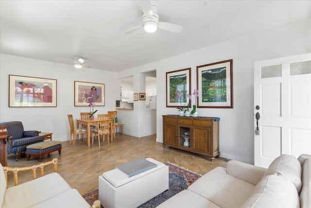 living room with ceiling fan and baseboards