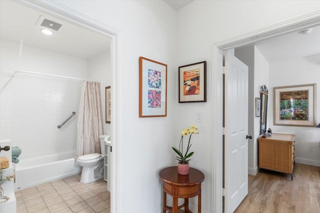 bathroom with toilet, visible vents, baseboards, tile patterned floors, and shower / tub combo with curtain