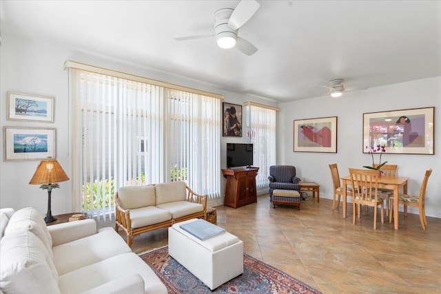 living room featuring baseboards, a ceiling fan, and a wealth of natural light