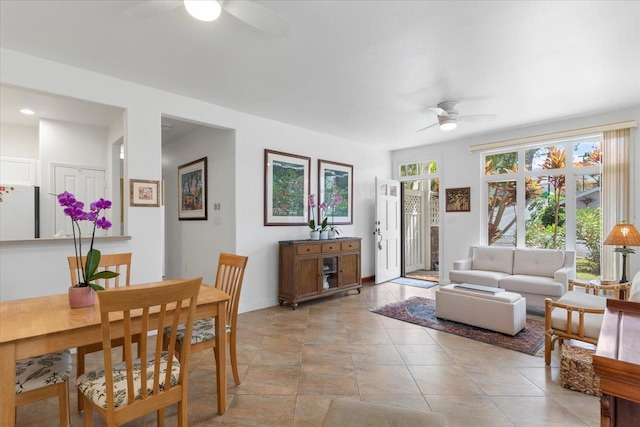 living area with ceiling fan, light tile patterned flooring, a wealth of natural light, and baseboards