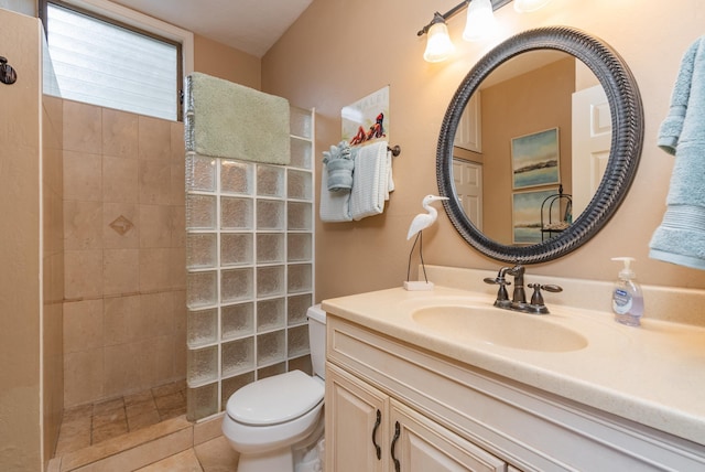 bathroom with toilet, vanity, tiled shower, and tile patterned floors