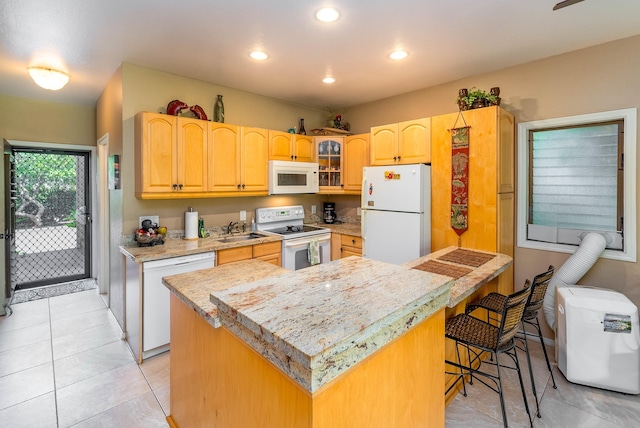 kitchen featuring a center island, sink, white appliances, a breakfast bar area, and light tile patterned floors