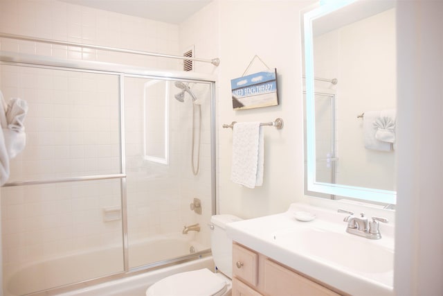 full bathroom featuring vanity, combined bath / shower with glass door, and toilet