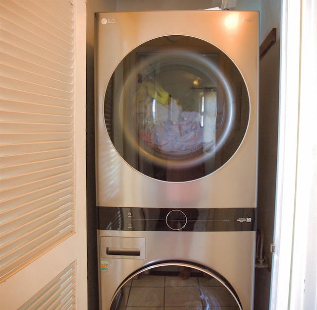 clothes washing area with tile patterned flooring and stacked washer and dryer