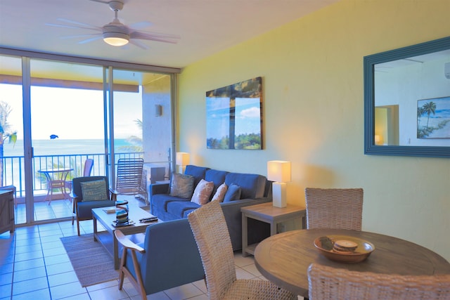 tiled living room featuring ceiling fan, floor to ceiling windows, and a water view