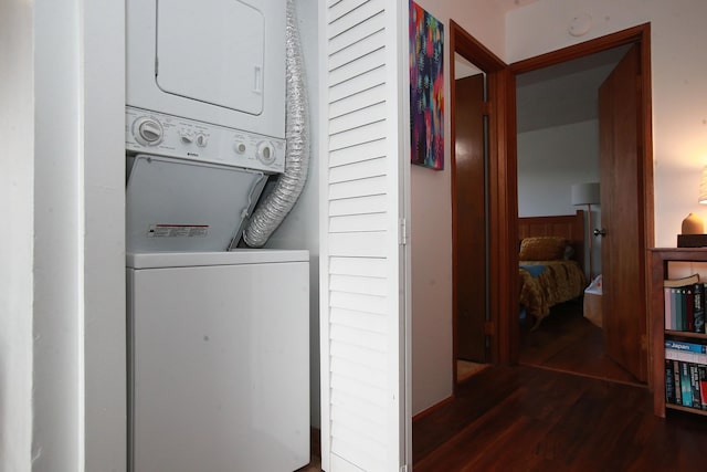 laundry room featuring dark hardwood / wood-style flooring and stacked washer / dryer