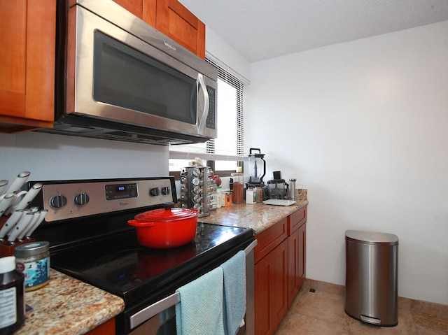 kitchen featuring light stone counters, light tile patterned floors, and stainless steel appliances