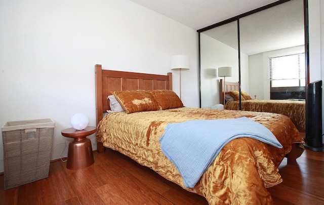 bedroom with wood-type flooring, a textured ceiling, a closet, and lofted ceiling