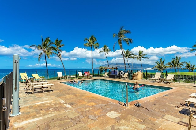pool featuring a patio, a water view, and fence