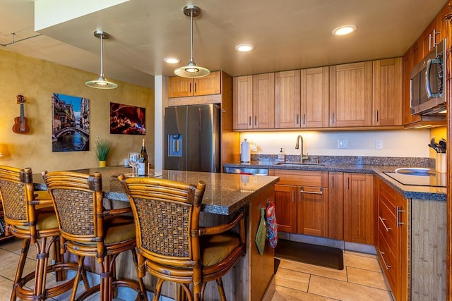 kitchen with a breakfast bar, stainless steel appliances, decorative light fixtures, a sink, and light tile patterned flooring