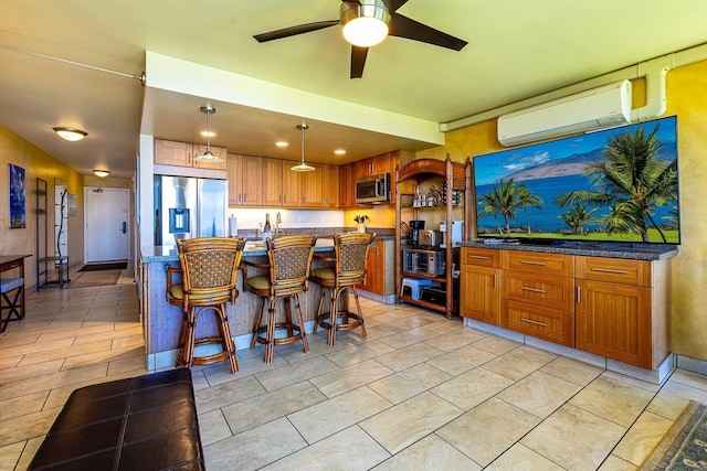 kitchen featuring a wall unit AC, appliances with stainless steel finishes, ceiling fan, a kitchen bar, and hanging light fixtures