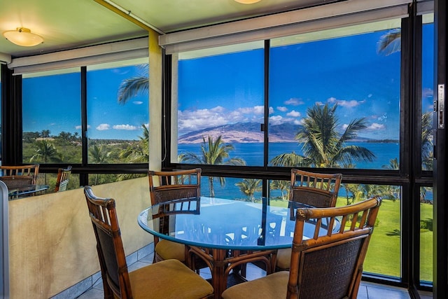 sunroom / solarium with tile patterned floors and a water view