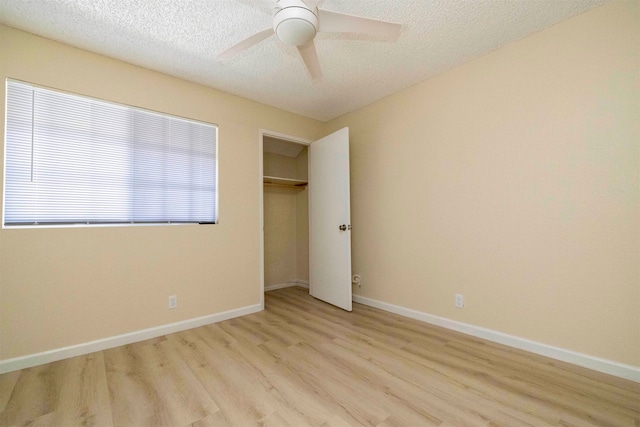 unfurnished bedroom with a textured ceiling, a closet, light wood-type flooring, and ceiling fan