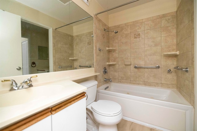 full bathroom with tiled shower / bath, hardwood / wood-style flooring, vanity, and toilet