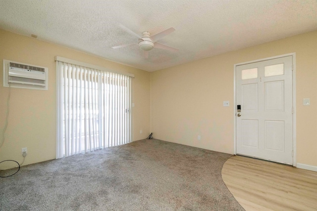 interior space featuring ceiling fan, a textured ceiling, light hardwood / wood-style floors, and a wall mounted air conditioner