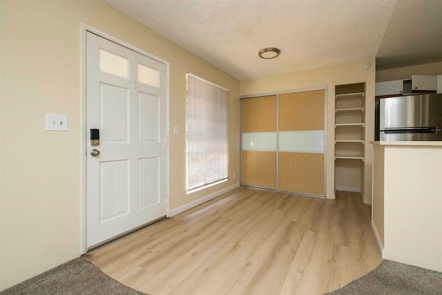 entryway featuring a textured ceiling and light hardwood / wood-style flooring