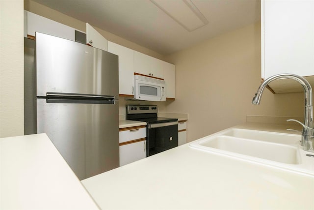 kitchen with appliances with stainless steel finishes, sink, and white cabinetry